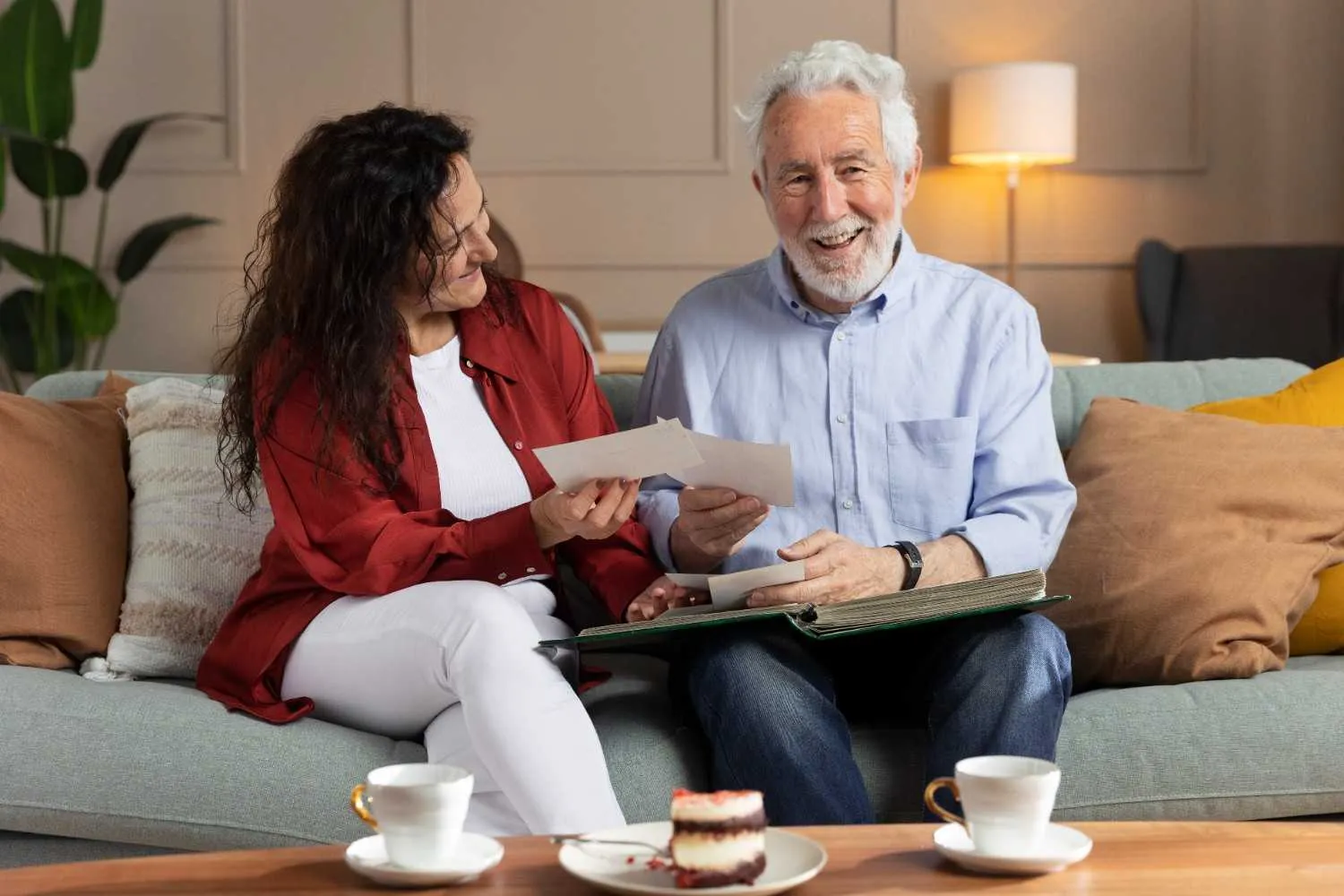Two people smiling while looking through papers together on a sofa